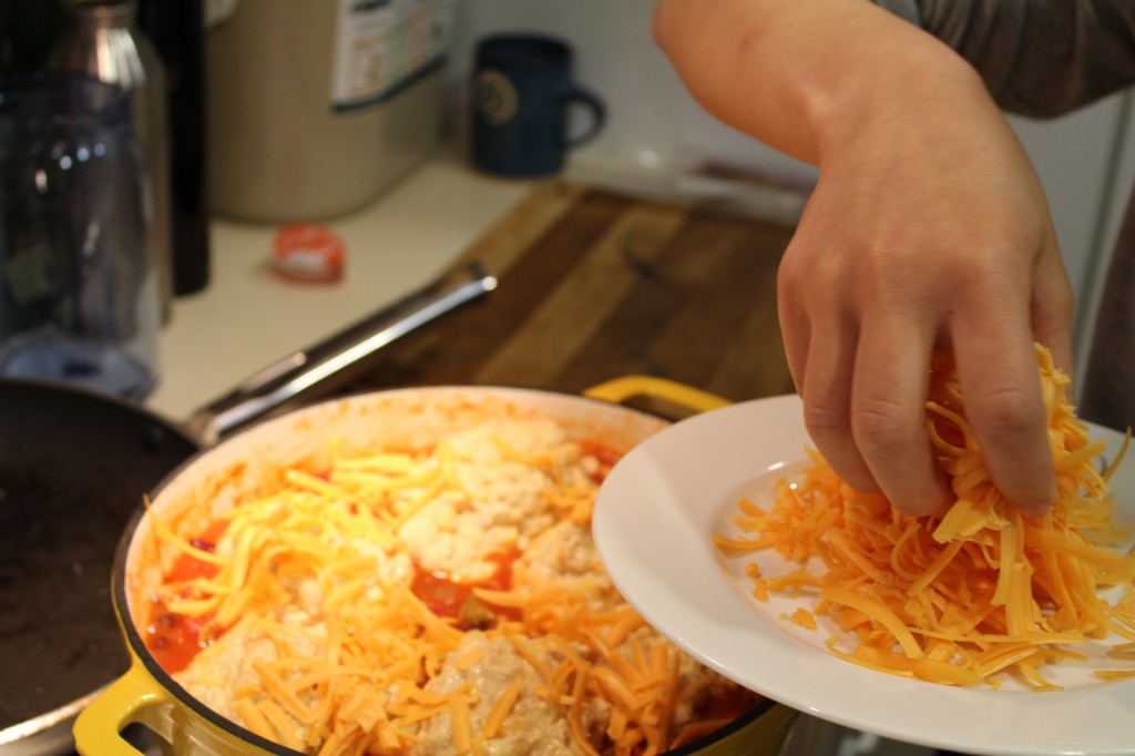 Putting the cheese on before it goes in the oven.