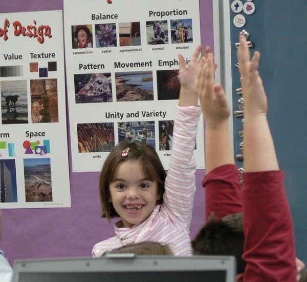 child with hand up in classroom